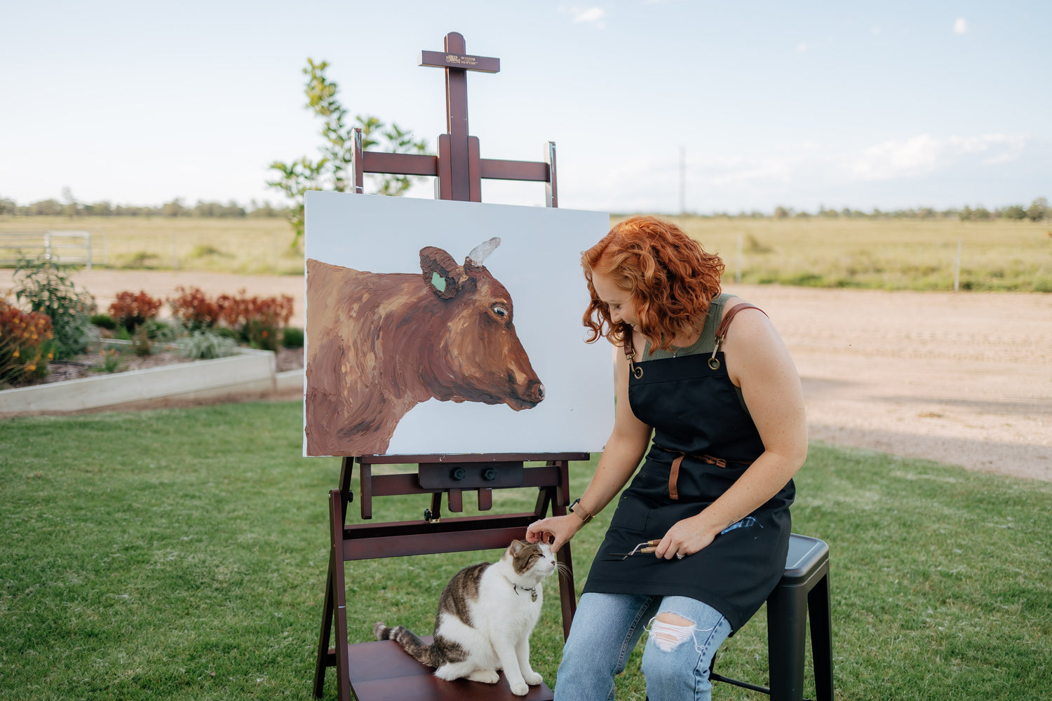 Julia Proud-Maher in front on canvas patting cat